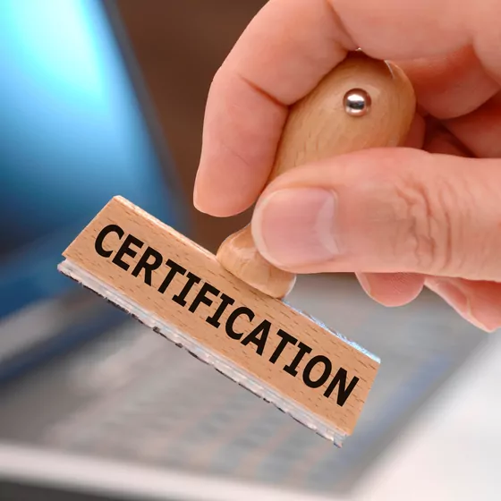 Hand holding a wooden stamp marked Certification