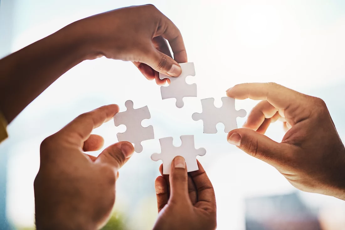 Hands fitting puzzle pieces together